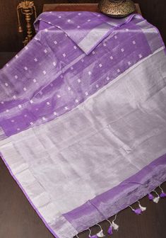 A Shobitam exclusive creation that will charm one and all with its color and shimmer! Set in a unique Silver tissue and linen interweave that you are not to find elsewhere, this Lavender hue saree comes with the breathability of natural linen and the shimmer of tissue! Thread buttas add texture, while the grand tissue pallu and Silver zari border finished with long tassels makes a grand statement! This saree is ready to wear with fall and pico done. Handmade long tassels adorn the pallu and add Silver Tissue Silk Dupatta For Festivals, Silver Handloom Dupatta For Festivals, Festivals Silver Handloom Dupatta, Silver Handloom Dupatta For Festive Occasions, Festive Silver Handloom Dupatta, Festive Linen Saree With Zari Weaving, Festive Linen Dupatta With Zari Work, Festive Linen Dupatta With Traditional Drape, Linen Cutdana Saree For Festive Occasions