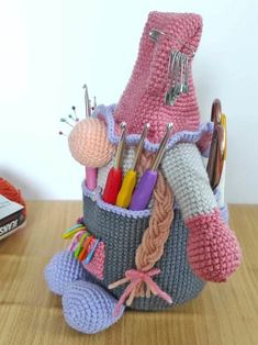 a crocheted basket filled with lots of crafting supplies on top of a wooden table