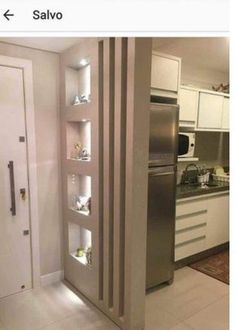 a stainless steel refrigerator in a kitchen with white cupboards and drawers on the wall