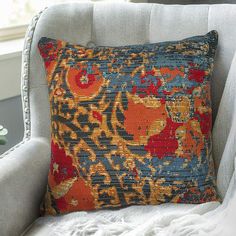 a blue and orange pillow sitting on top of a white chair next to a window