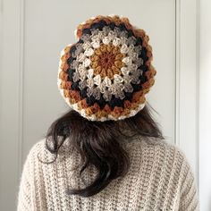 a woman is wearing a crocheted hat in front of a door