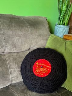 a black crocheted hat sitting on top of a couch next to a potted plant