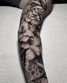 black and white flower tattoo on the arm, with an image of a woman's legs