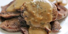 some meat with gravy on top of it is sitting on a white plate