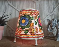 an elephant figurine is sitting next to a lamp shade on a wooden table