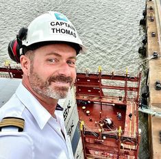 a man wearing a hard hat standing in front of a ship