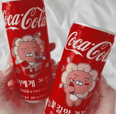 two cans of coca - cola are shown in this photo