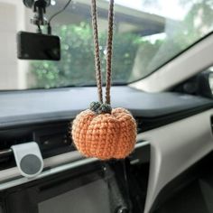 an orange crocheted apple hanging from a car dashboard