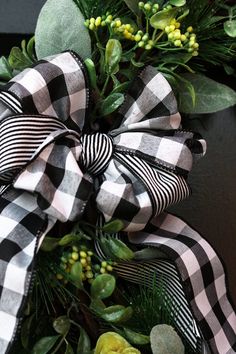 a black and white bow with green leaves on the front door for wreaths or christmas decorations