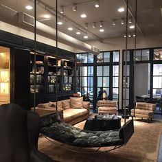 a living room filled with lots of furniture next to tall glass doors and windows on the wall