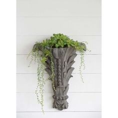 a planter hanging on the side of a wall with plants growing out of it