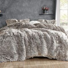 a bed covered in grey fur next to a window