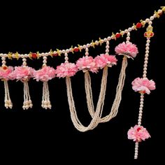 pink flowers and pearls are hanging from the side of a long string with beads on it