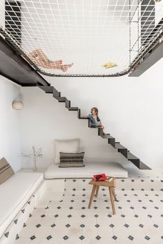 there is a woman sitting on the stairs in this living room with white walls and flooring