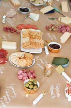 a table topped with lots of different types of cheeses and crackers on plates