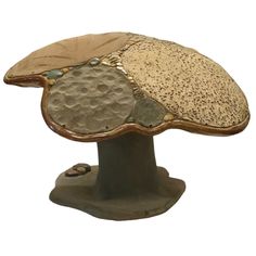 a ceramic mushroom sitting on top of a wooden base with lots of different colors and shapes