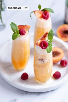 two glasses filled with drinks and garnished with raspberries on a plate