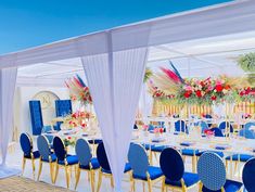 an outdoor wedding setup with blue chairs and white drapes