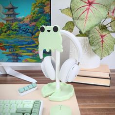 a frog headphone holder sitting on top of a desk next to a keyboard and mouse