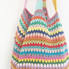 a multicolored crocheted bag hanging from a hook on a white wall