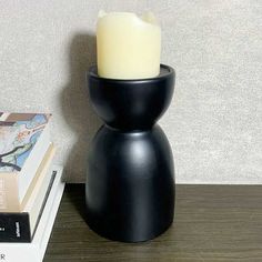 a black candle holder sitting on top of a table next to a stack of books