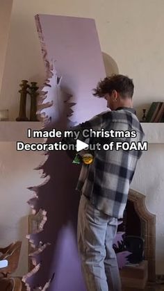 a man standing in front of a christmas tree that has been cut into the wall