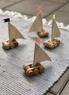 three small wooden sailboats sitting on top of a rug