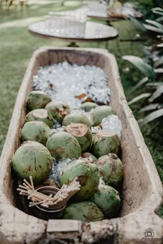 a wooden box filled with lots of coconuts on top of a grass covered field