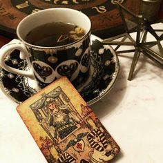 a cup of tea next to a tarot card on a saucer and plate