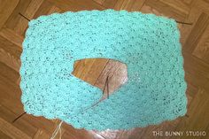 a blue crocheted rug sitting on top of a wooden floor next to a pair of scissors