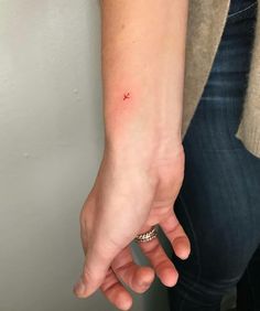 a woman's hand with a tiny red dot on the middle of her wrist