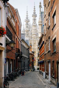 a narrow street with bicycles parked on both sides and buildings in the backround