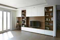 a living room with white cabinets and a flat screen tv on top of a wooden entertainment center