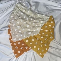 three pieces of cloth are laid out on a bed sheet with white and brown flowers