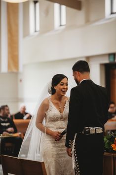 a bride and groom smile as they stand at the alter