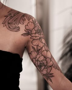 a woman's arm with flowers and leaves on the back of her shoulder,