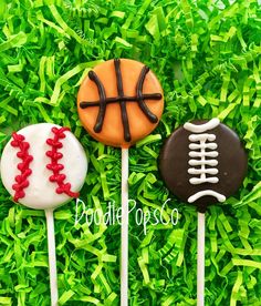 three decorated cake pops sitting on top of green grass next to each other with sports themed frosting