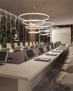 a long table with several laptops on it in front of a wallpapered background