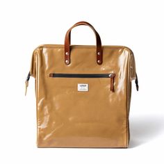 a tan leather bag with brown handles and two zippers on the front, sitting against a white background