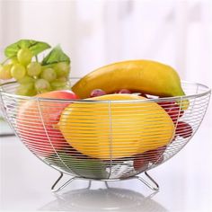 a bowl filled with fruit sitting on top of a table next to grapes and bananas