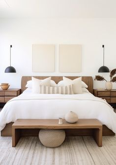 a bed with white linens and pillows in a modern bedroom, with two lamps on either side of the bed