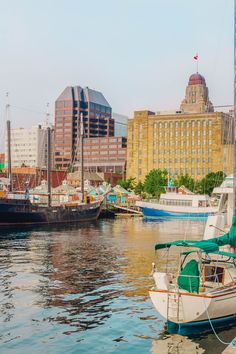 several boats are docked in the water near some buildings and other large cityscapes