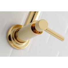 a close up of a faucet on a wall mounted shower head with gold fixtures