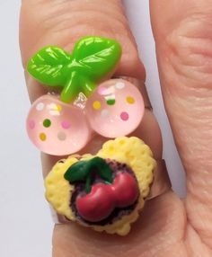 a person's hand with a ring made to look like an apple and strawberry