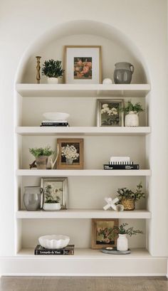 a white book shelf filled with lots of books and vases on top of it