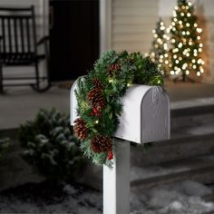 a mailbox decorated with pine cones and holly wreaths