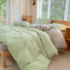 a bed with green and white checkered comforter in a bedroom next to a window