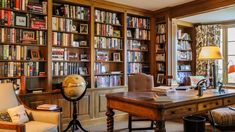 a large library with many bookshelves and chairs in the room, along with two lamps on either side of the bookcases