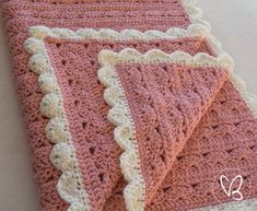 two pink and white crocheted blankets sitting on top of each other