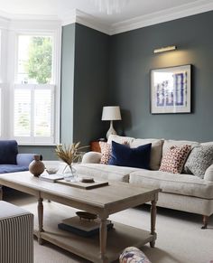 a living room filled with furniture and a painting on the wall above it's windows